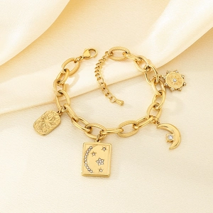 Macro detail of gold star and moon charms with zircon on a bold curb chain bracelet