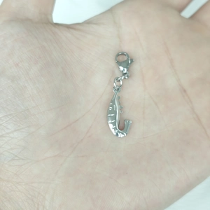 Macro shot of silver hollow fish pendant with lobster clasp held in palm for scale