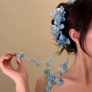 Detail of blue flower hair claw clip with pearl chain and fabric butterfly on model