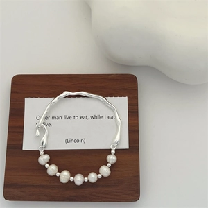 Detail of baroque freshwater pearls combined with a wavy silver branch bracelet