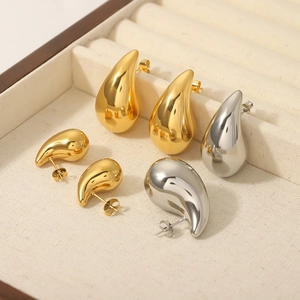 Polished 18K gold and silver teardrop earrings set in a velvet jewelry display box