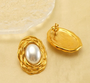 Detailed close-up of woven gold titanium earrings with large oval pearls and brushed back texture