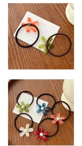 Detail view of colorful acetate flower hair ties with pearls on a rustic wooden tray