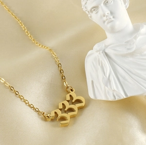Detailed view of number 333 gold-plated stainless steel necklace on beige silk