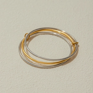 Detail of layered stainless steel bangles in gold and silver finish on stone texture