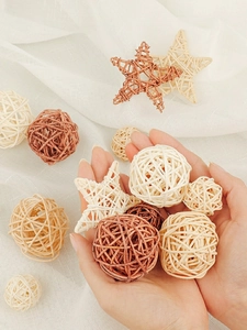 Macro shot of assorted beige and brown rattan balls and stars held in hands over white fabric