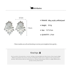 Detailed view of white fringe earrings made of acrylic beads and artificial pearls