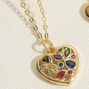 Macro shot of gold heart pendant necklace inlaid with vibrant colorful zircon gemstones