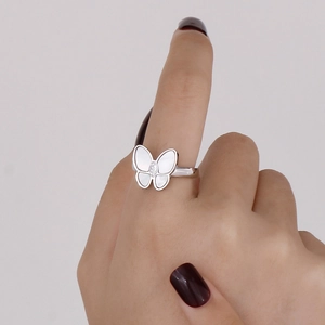 Detailed close-up of a silver butterfly ring with white shell inlay on a model's finger