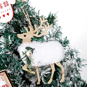 Wooden Christmas reindeer ornament with faux fur details hanging on a snowy Xmas tree