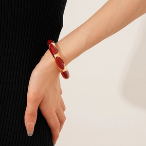Detail of a vintage French oval red enamel gold cuff bracelet worn on a female wrist