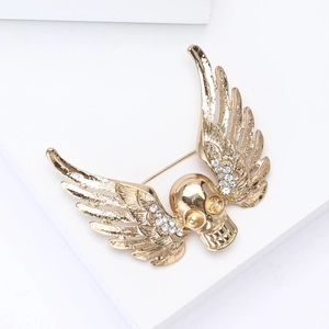 Macro detail of golden skull and wings brooch with sparkling white rhinestones