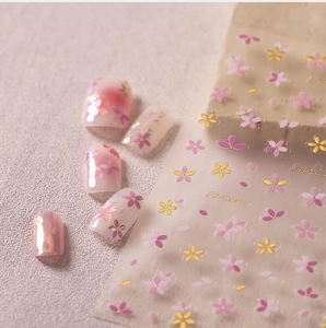 Detail of embossed cherry blossom nail stickers with gold outlines on nude pink nails