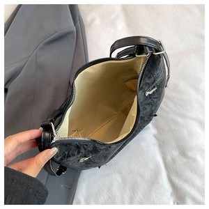 Top view of large black crossbody bag showing marble texture leather and beige lining interior