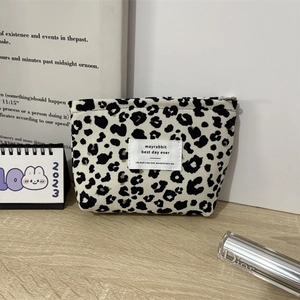 Close-up of leopard print corduroy makeup bag with zipper closure on a wooden desk