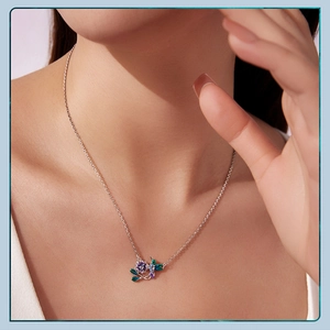 Close-up of a silver hummingbird and flower necklace worn by a professional model