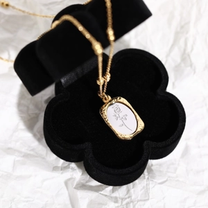 Detailed view of vintage gold rose pendant necklace in a black velvet flower box