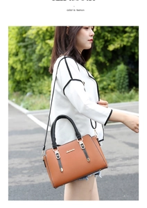 Brown textured leather handbag with black handles and gold hardware shown on a model