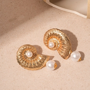 Detailed view of vintage gold shell earrings with white imitation pearls and embossed texture