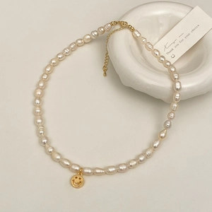 Detail of freshwater pearl necklace with golden smiley face pendant and lobster clasp