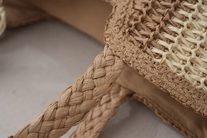 Close-up of brown handles and straw texture on vertical striped tote bag