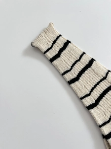 Detail der Stricktextur und der schwarz gestreiften Manschette an diesem Midi-Kleid