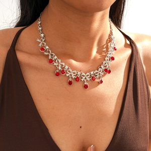 Close-up of double layer silver necklace with red crystals and bow pendant on neck