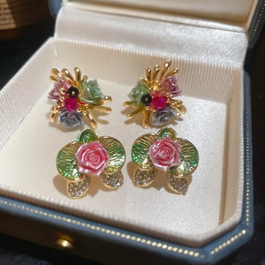 Detailed macro view of colorful enamel flower earrings set in a beige velvet jewelry box