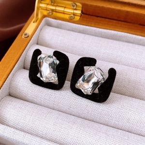 Macro view of geometric square velvet earrings with inset crystal in a jewelry box