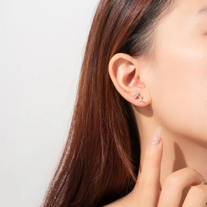 Close-up of a model wearing a minimalist silver daisy flower stud earring on the ear