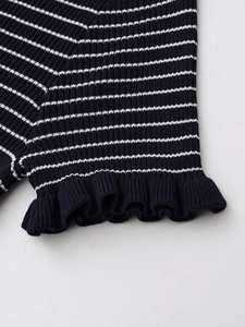 Détail de la manche en maille rayée bleu marine et blanc avec bordure à volants et côtes