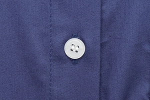 Close-up of white resin button and deep blue twill fabric texture on a women's shirt