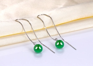 Macro detail of silver tassel chain earrings with smooth green agate sphere pendants