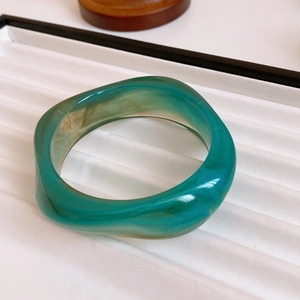Detailed view of vintage green resin bangle with gold plating on a jewelry display tray