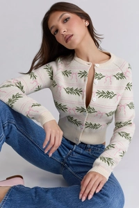 Close-up of knit cardigan texture with green leaves and pink bow jacquard patterns