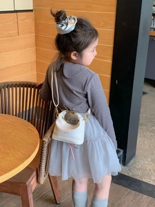 Girl's white mini PU leather shoulder bag with gold chain strap shown on a model