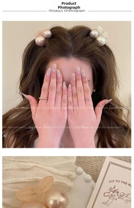 Detail of sweet cherry-style resin bow hair clips and minimalist golden rings