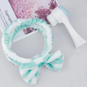 Detailed set of a soft striped plush bow headband and a dual-sided silicone face brush