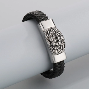 Macro detail of men's black braided leather bracelet with silver lion head clasp