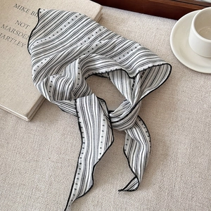 Flat lay of vintage striped scarf necklace on fabric with a coffee cup and book
