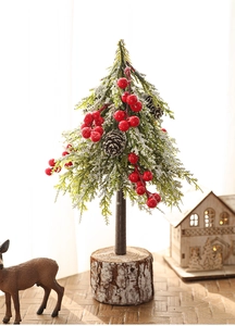 Detailed view of mini Christmas tree with snow, red berries and natural wooden base