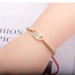 Adjustable red string bracelet with gold beads and a sparkling zircon heart lock charm