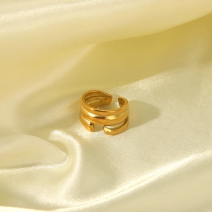 Close-up of golden multi-layer irregular hammered ring on yellow silk fabric background