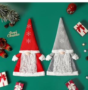 Detail of red and gray knitted Christmas gnomes with snowflake embroidery on green background