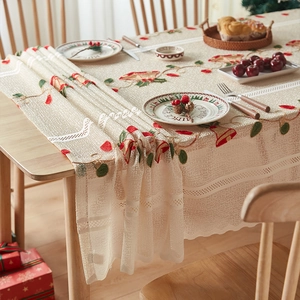 Close-up of festive red and green Christmas bell embroidery on beige lace tablecloth