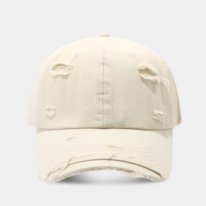 Detailed macro view of the distressed ripped edges on a beige vintage baseball cap