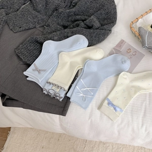Détail de chaussettes en coton avec bordure en dentelle, nœuds et motifs à pois pastel
