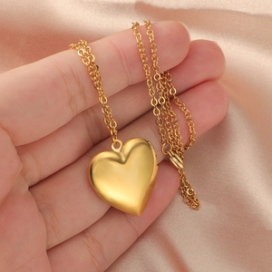 Close-up of golden heart locket necklace with delicate chain on champagne silk