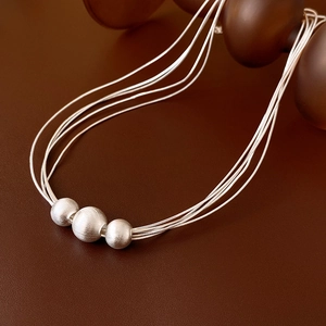 Detail of silver multi-layer necklace with frosted metal beads on leather surface
