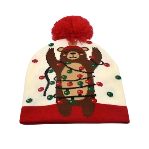 Close-up detail of knitted Christmas beanie with festive brown bear and colorful light pattern